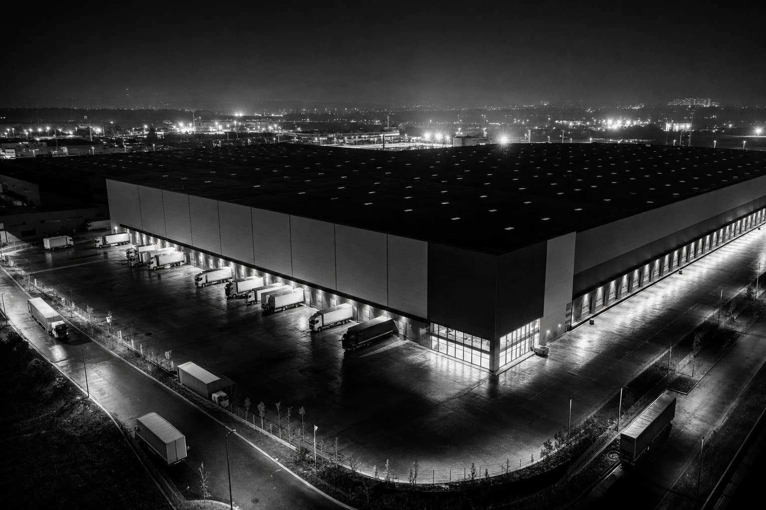 Logistički magacin noću sa kamionima na rampama